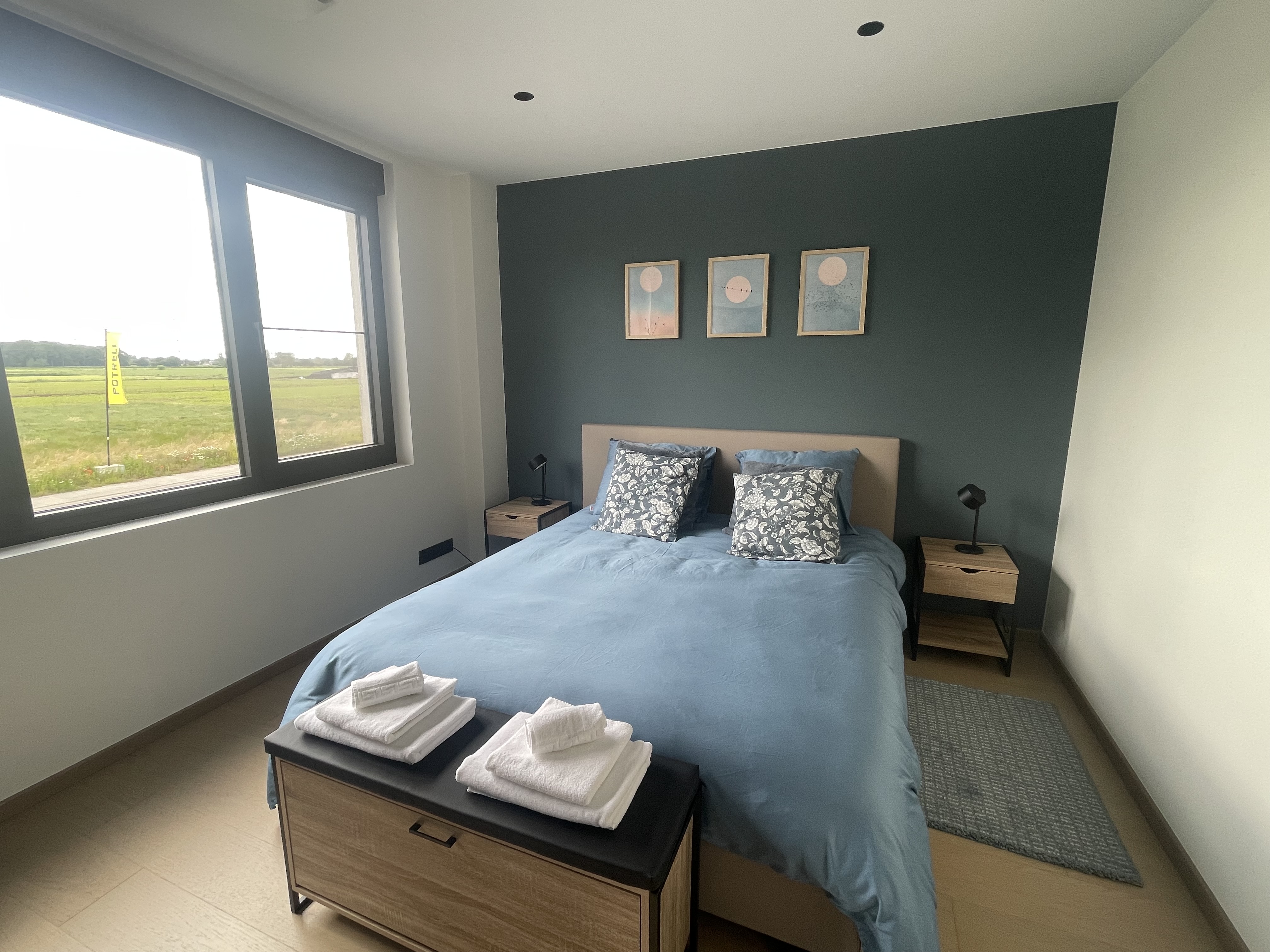 Blauwe slaapkamer met tweepersoonsbed en uitzicht op de velden