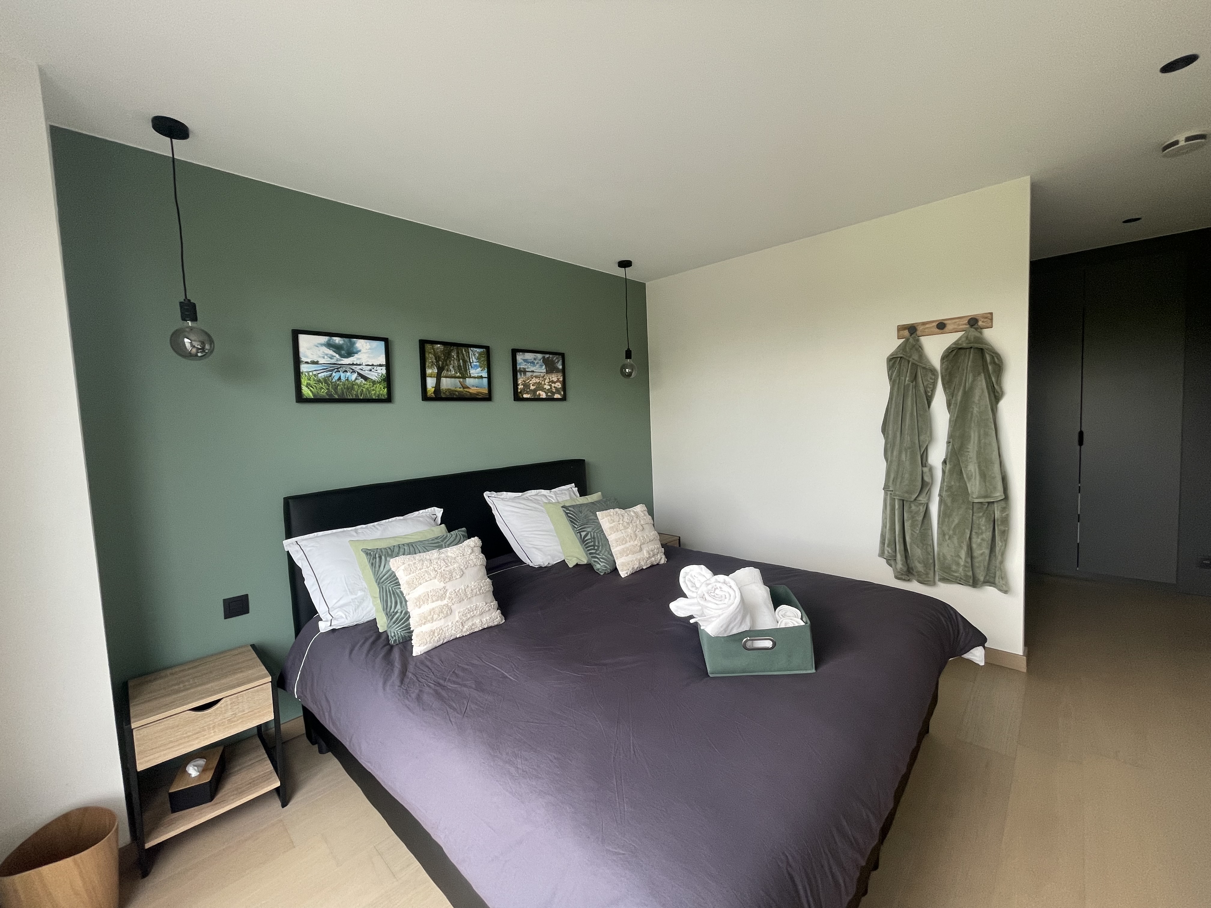 Groene master slaapkamer met groot tweepersoonsbed en badjassen